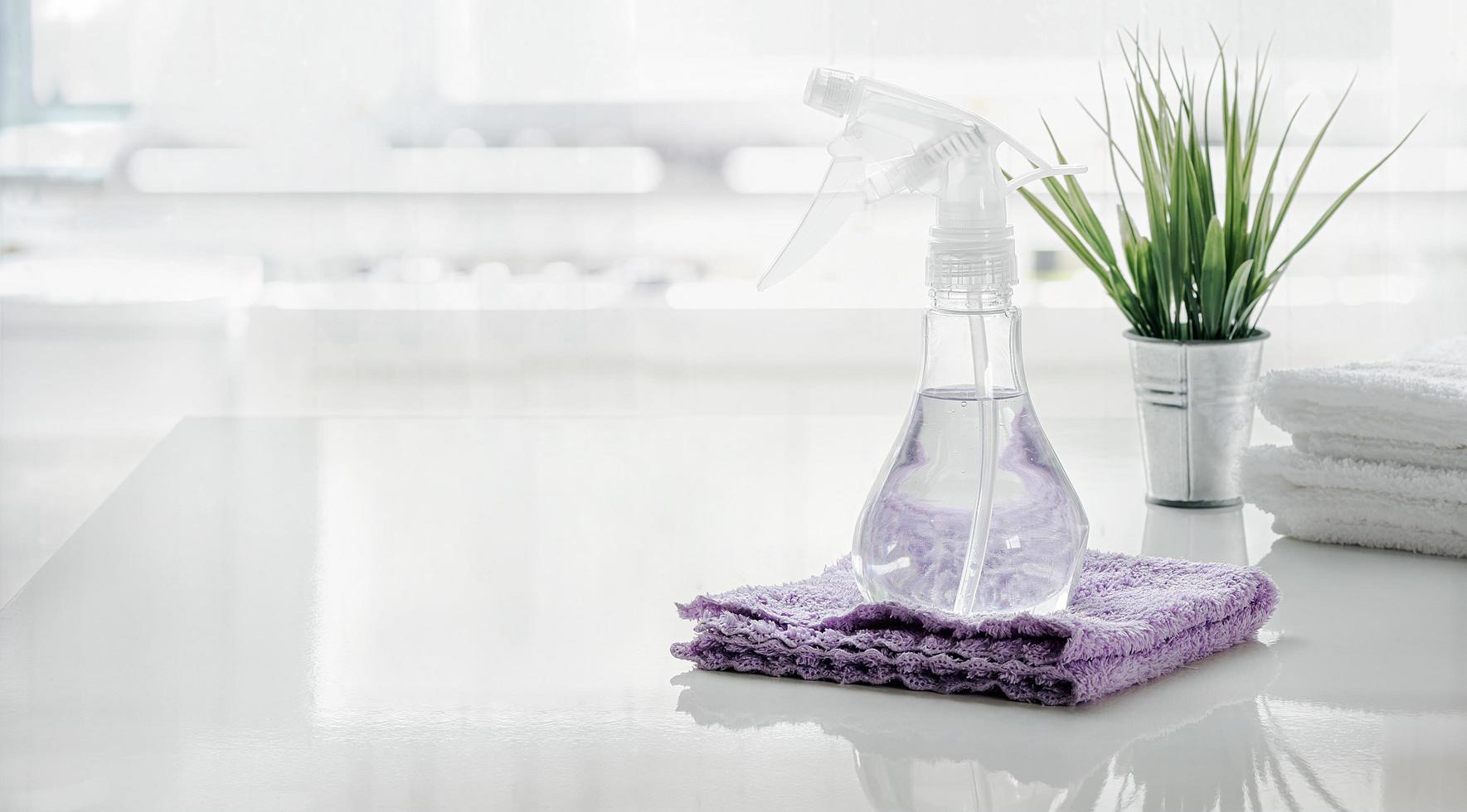 spray fles en handdoek op witte tafel in de keuken foto