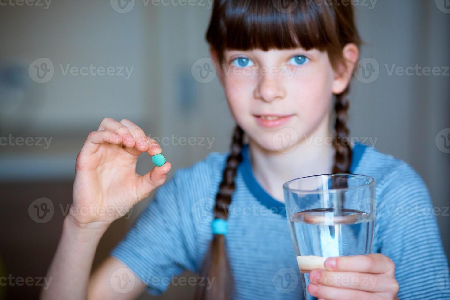 capsules, pillen in een hand, een glas van water in de ander. de meisje is Holding de geneeskunde in voorkant van haar. detailopname. foto