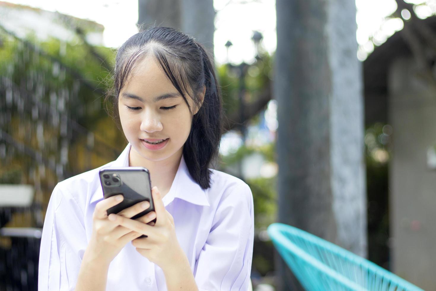 Thais meisje met behulp van een mobiele telefoon foto