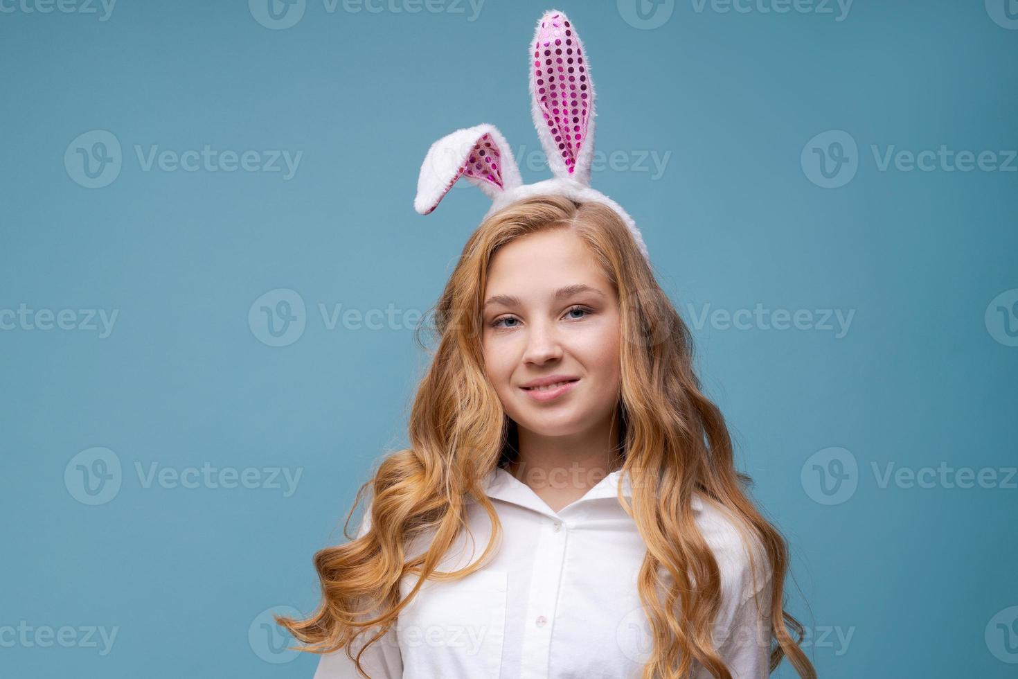 meisje in roze konijn oren Aan haar hoofd Aan blauw studio achtergrond. vrolijk foto