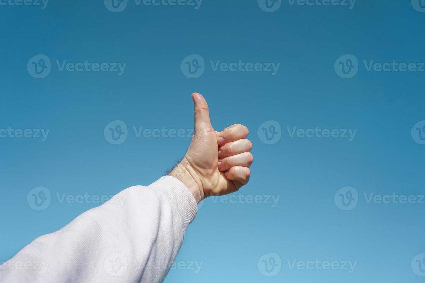 hand- omhoog in de lucht gebaren in de blauw lucht, blauw achtergrond foto