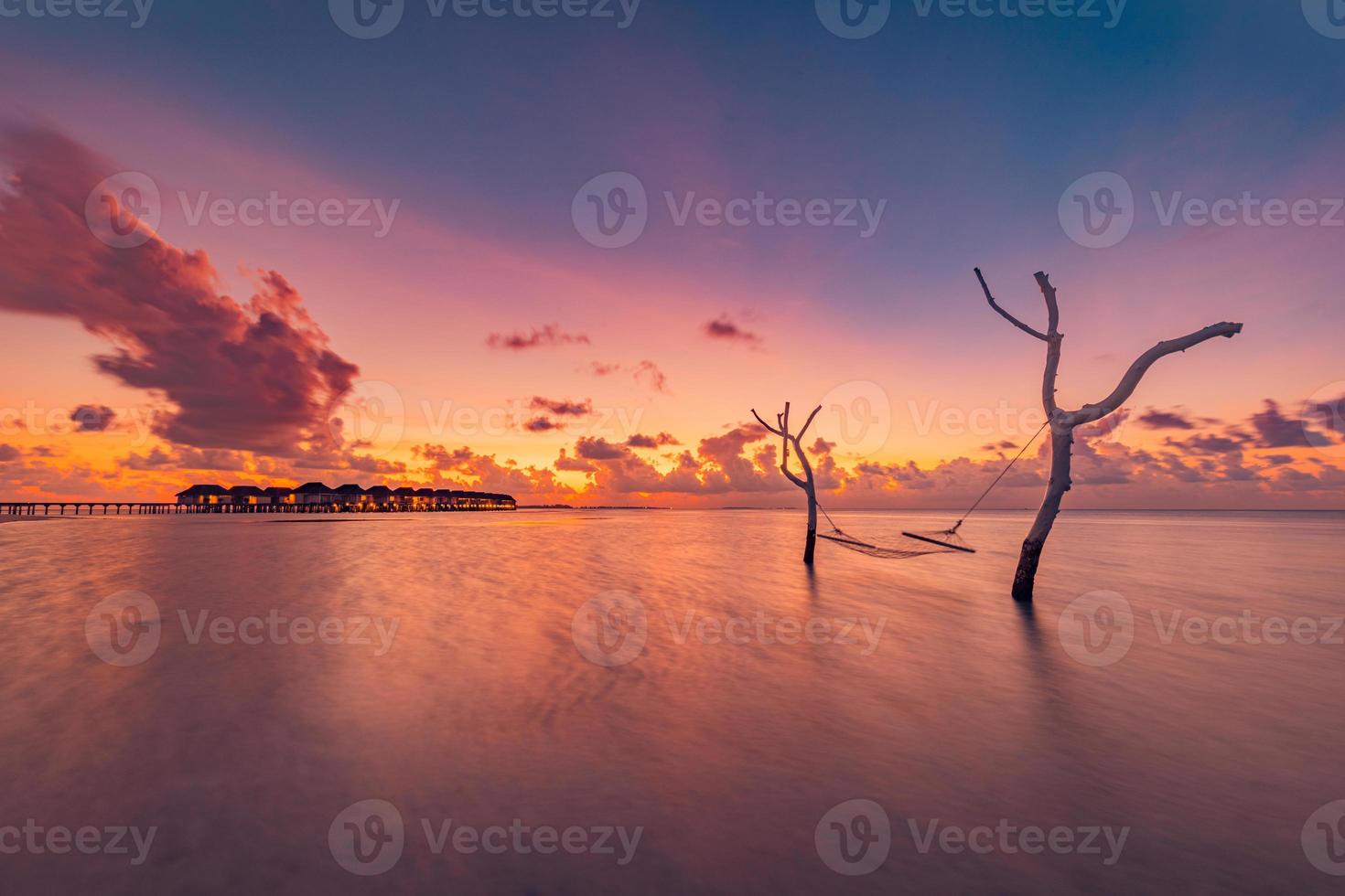 mooi helder zonsondergang Aan een tropisch paradijs strand. abstract lang blootstelling water en lucht, boom takken met schommel of hangmat. verbazingwekkend lagune, eiland oever, ontspanning, recreatie vrije tijd zorgeloos foto
