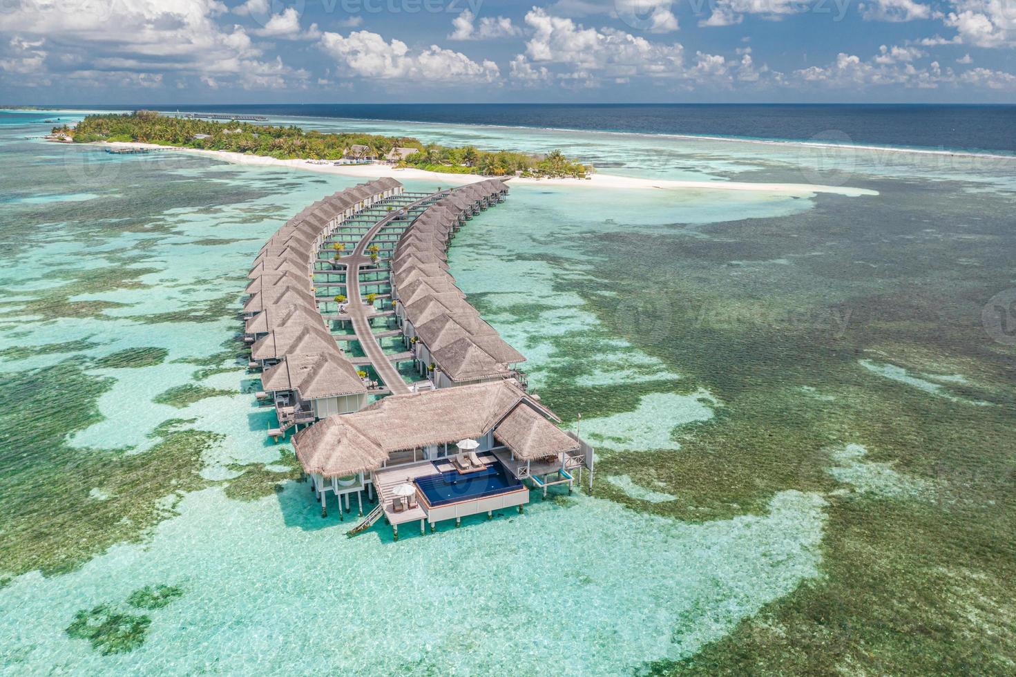 luchtfoto van het eiland maldiven, luxe watervilla's resort en houten pier. mooie hemel en oceaan lagune strand achtergrond. zomervakantie vakantie en reizen concept. paradijs lucht landschap pano foto