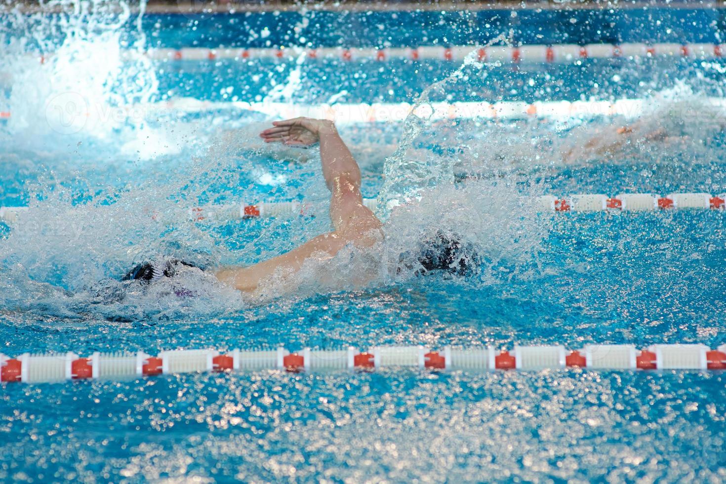 een muts zwemmer strekt zich uit uit zijn armen gedurende een schoolslag training in de zwembad, wazig focus foto