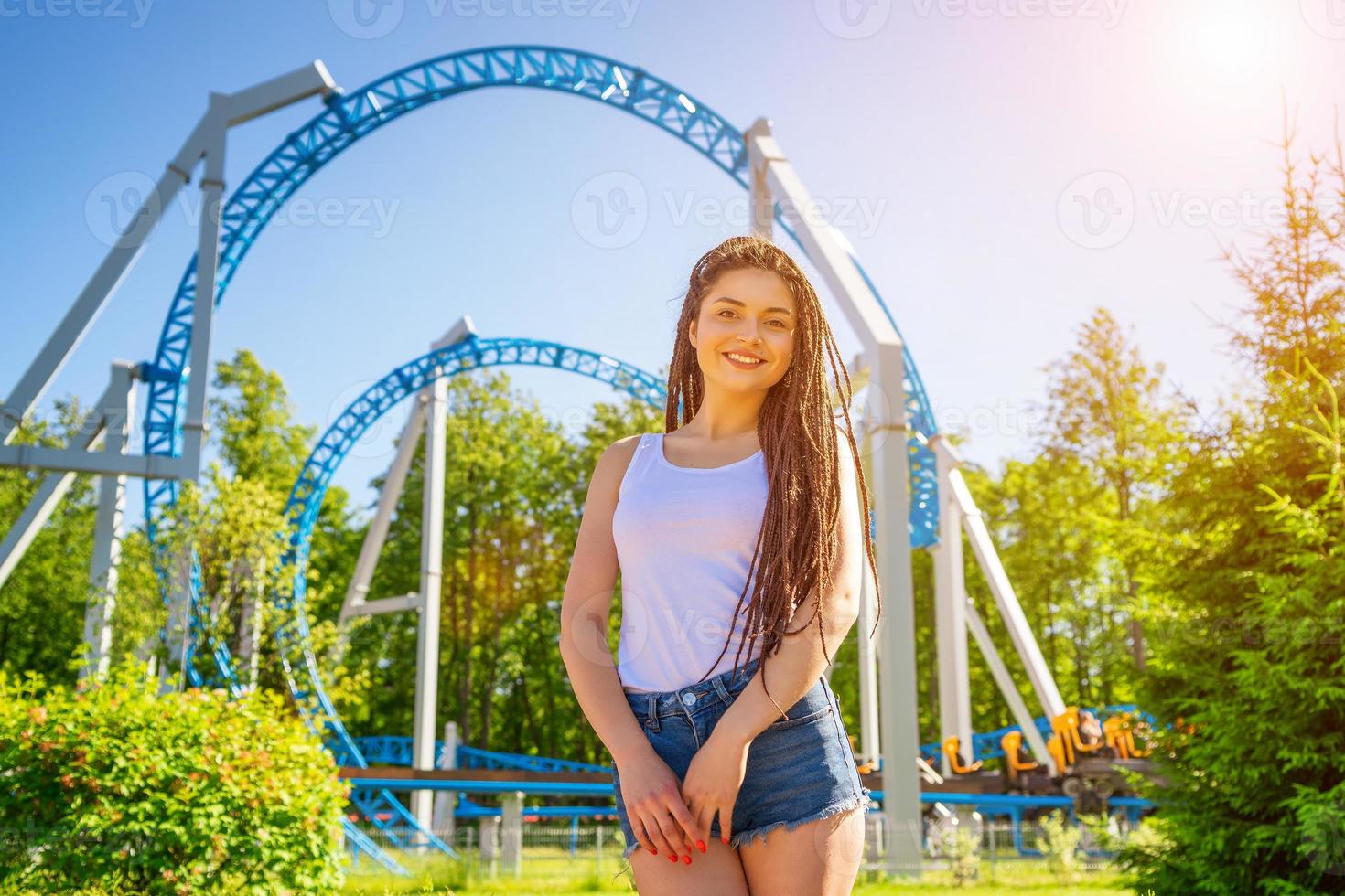 grappig meisje met dreadlocks Aan de achtergrond van een amusement park foto