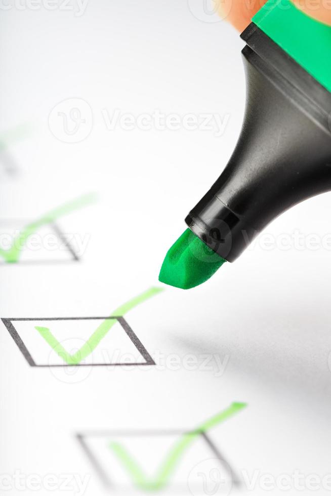 groen markeerstift met markeringen Aan de checklist vel. foto