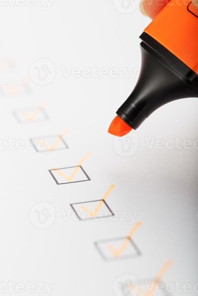 oranje markeerstift met markeringen Aan de checklist vel. foto