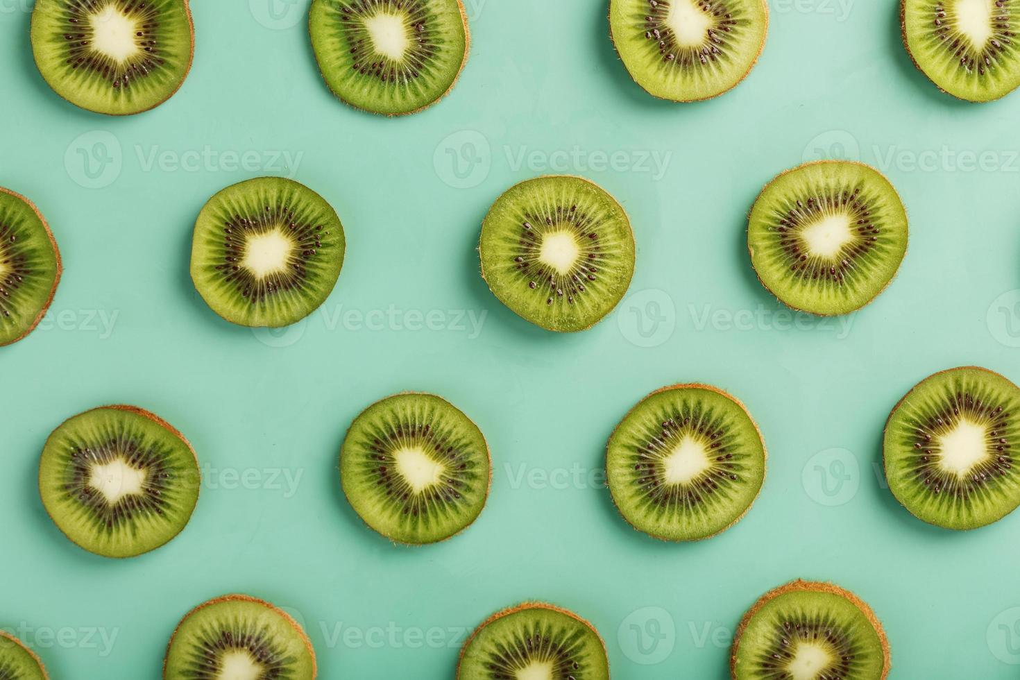 de patronen van de plakjes van kiwi fruit Aan groen achtergrond net zo een doorlopend achtergrond. foto