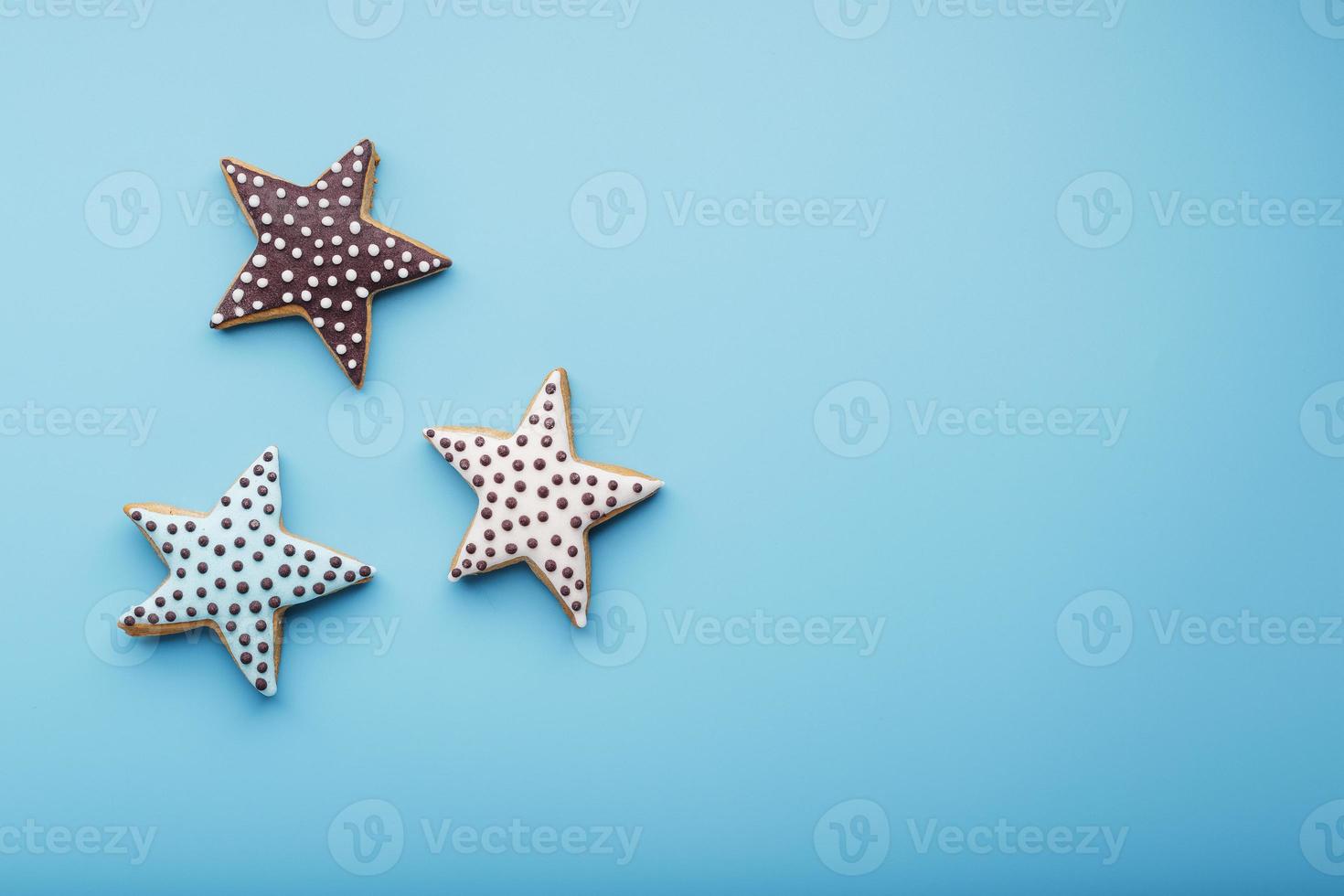 detailopname van drie eigengemaakt geglazuurd peperkoek koekjes gemaakt in de het formulier van sterren Aan een blauw achtergrond. handgemaakt koekjes. vrij ruimte. foto