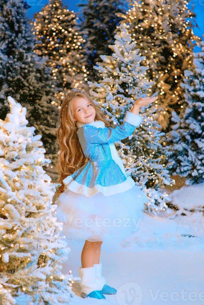 schattig blanke blonde meisje wandelen winter kerst bos met verlichting. nieuwjaar, sprookjesconcept foto