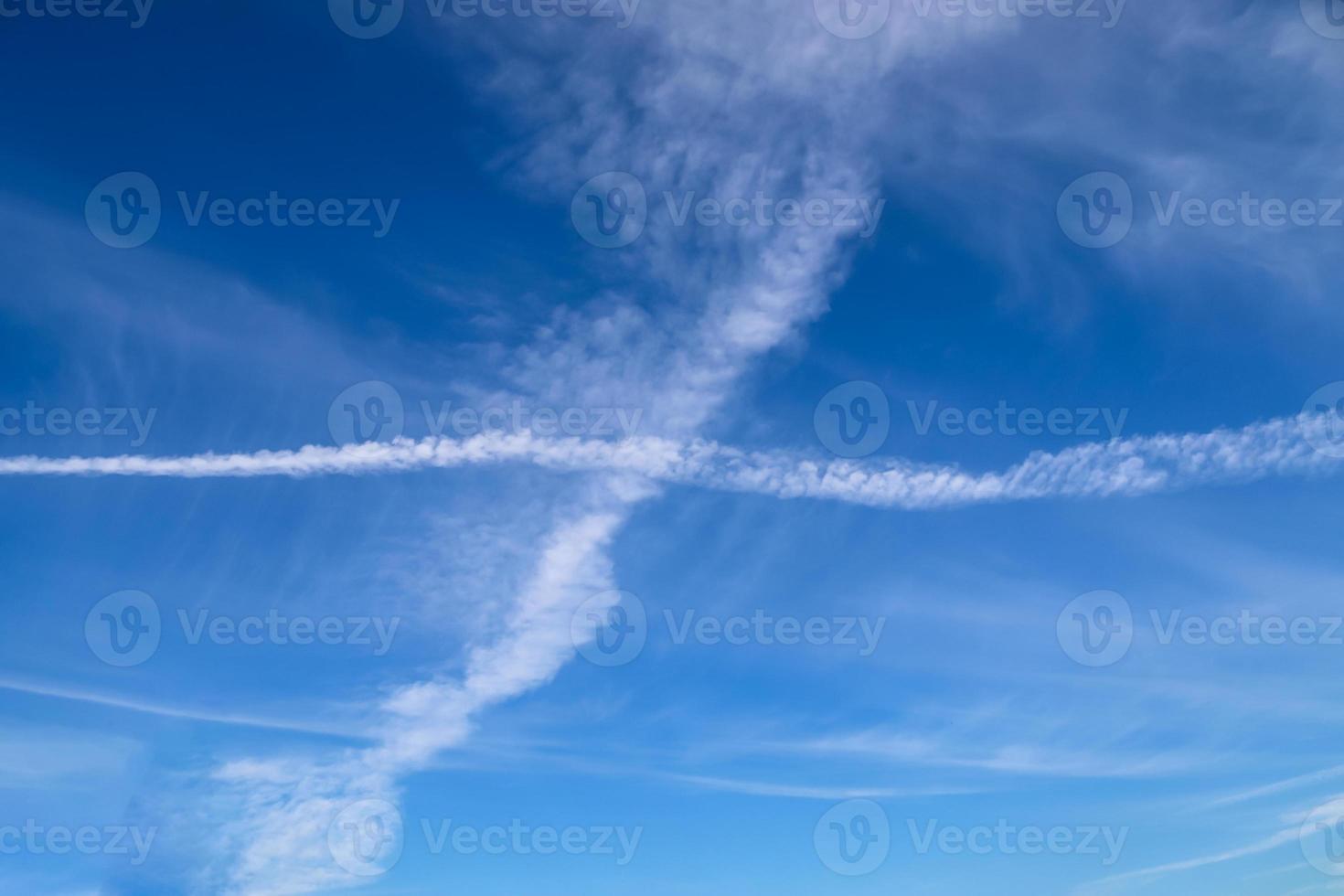 condensatiesporen van vliegtuigen in de blauwe lucht tussen enkele wolken foto