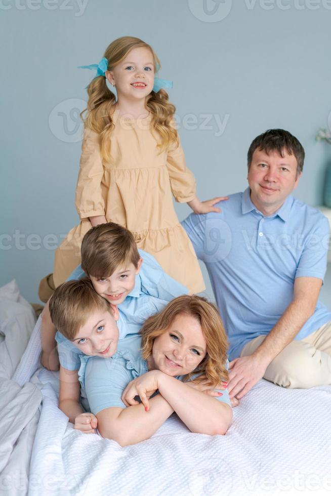 vrolijk familie spelen samen Aan bed. ouders besteden hun vrij tijd foto