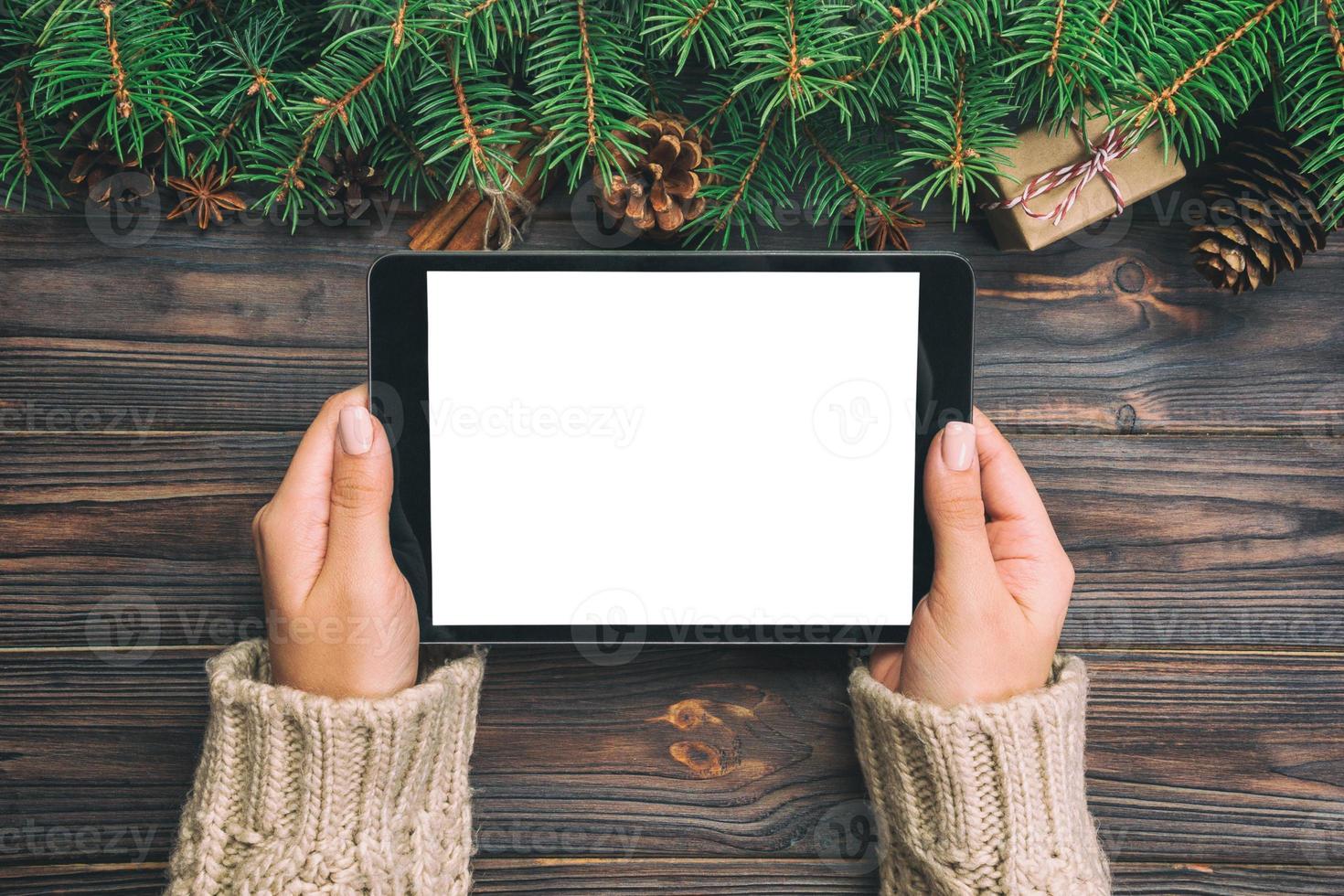 vrouw handen gebruik makend van tablet computer Aan houten tafel achtergrond. Kerstmis boodschappen doen tijd. gelukkig Kerstmis bespotten omhoog achtergrond, top visie. wijnoogst foto