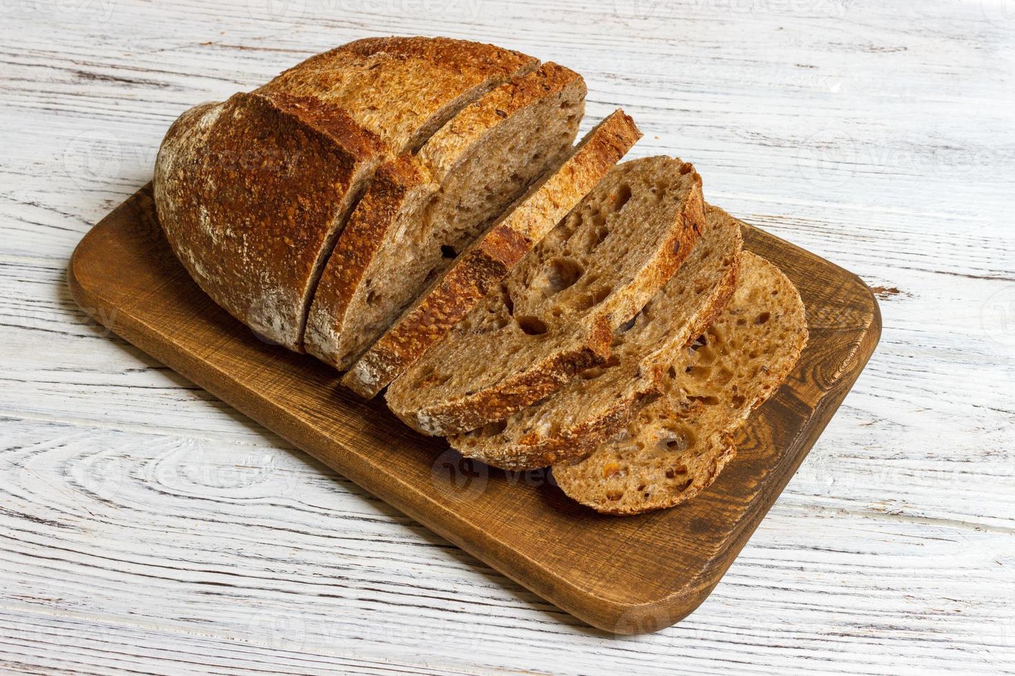 gesneden Frans brood Aan houten bord. wit houten achtergrond foto