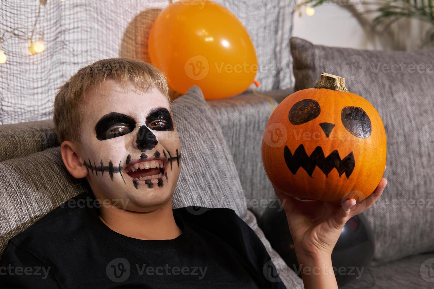 eng kind met een bedenken in het formulier van een skelet en met een pompoen in zijn handen foto