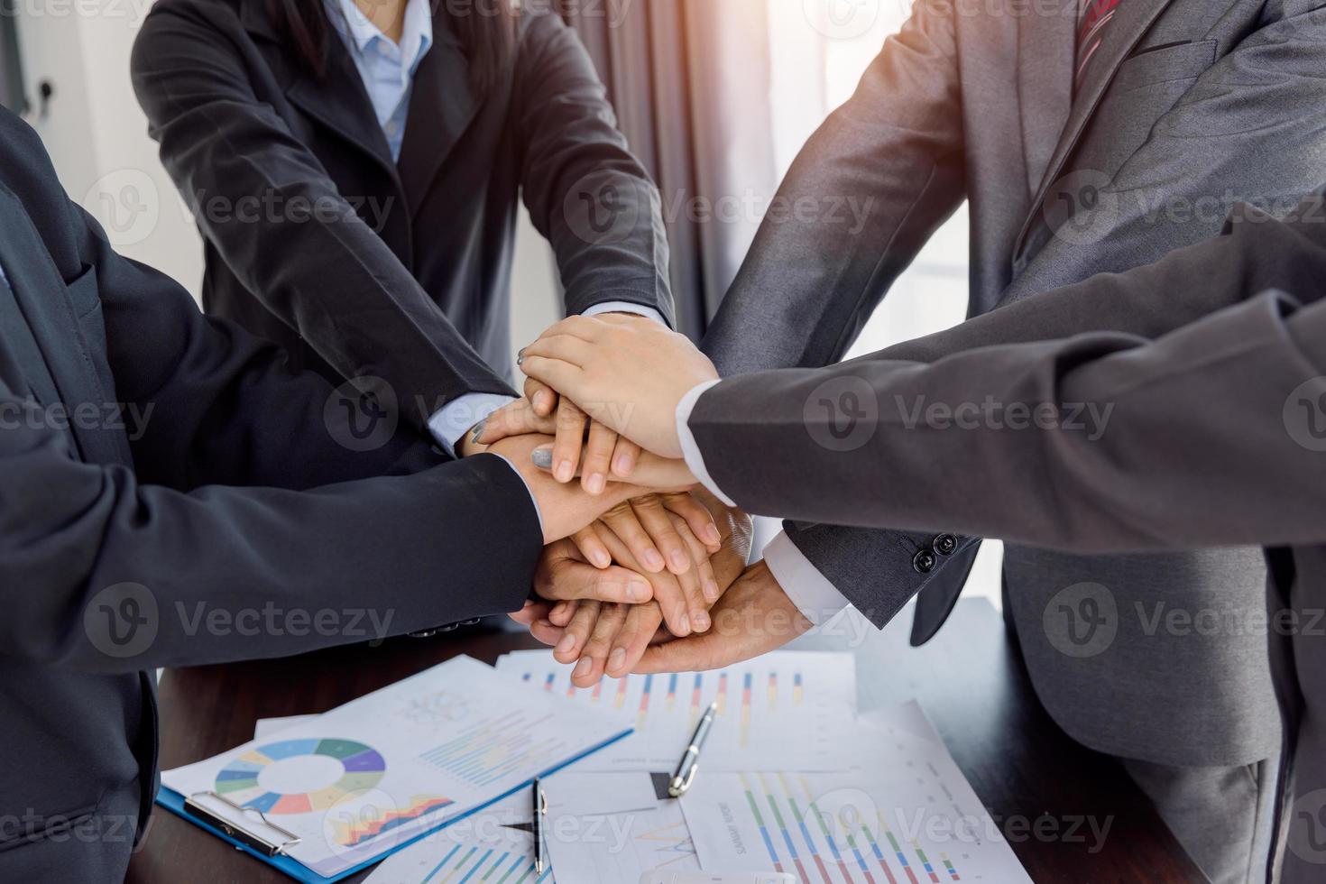 zakenmensen hand in hand boven bureau met gadgets, teamwork succesvolle vergadering werkplekstrategie met grafiek financieel diagram bovenaanzicht. foto