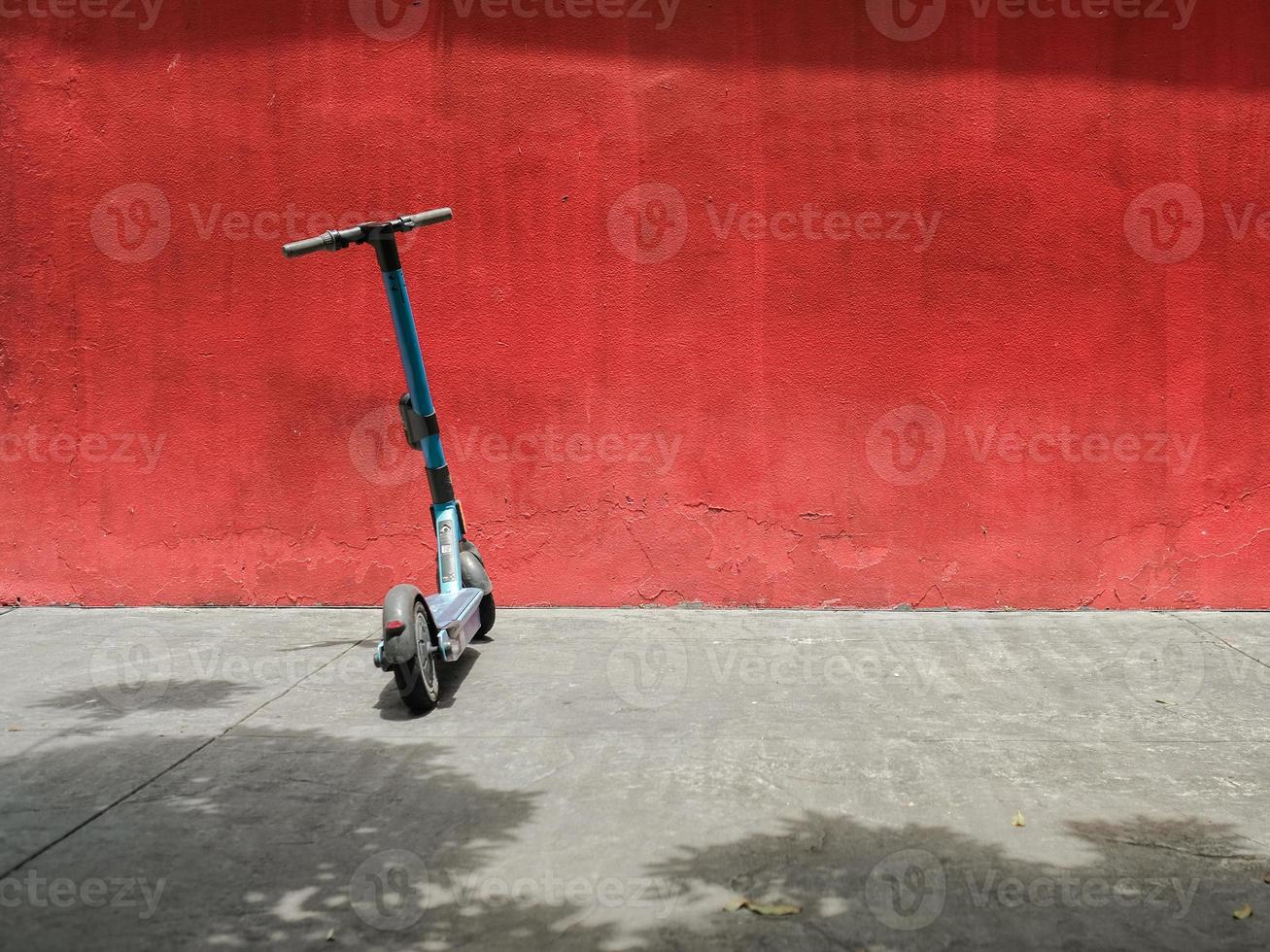ab elektrisch scooter geparkeerd in de zon tegen een rood muur foto