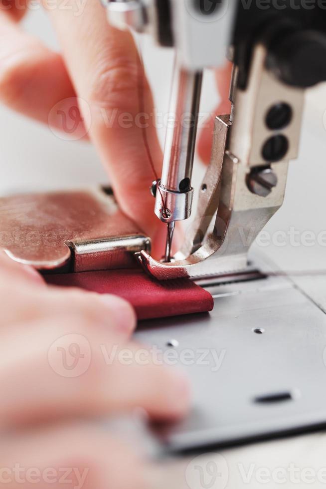 een leer vakman produceert leer goederen Aan een naaien machine in zijn winkel. foto