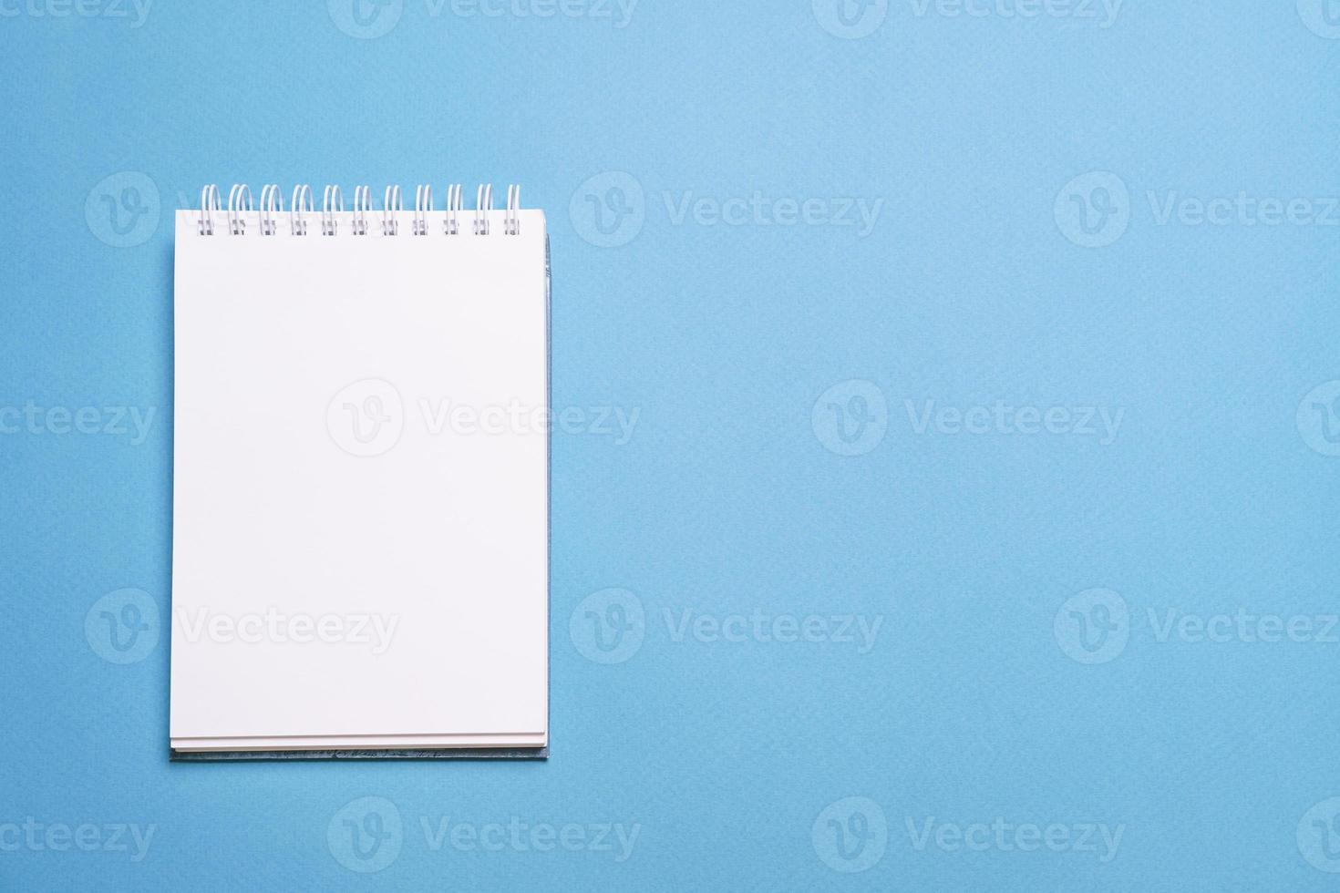 school- notitieboekje Aan blauw achtergrond, spiraal kladblok Aan tafel, onderwijs foto