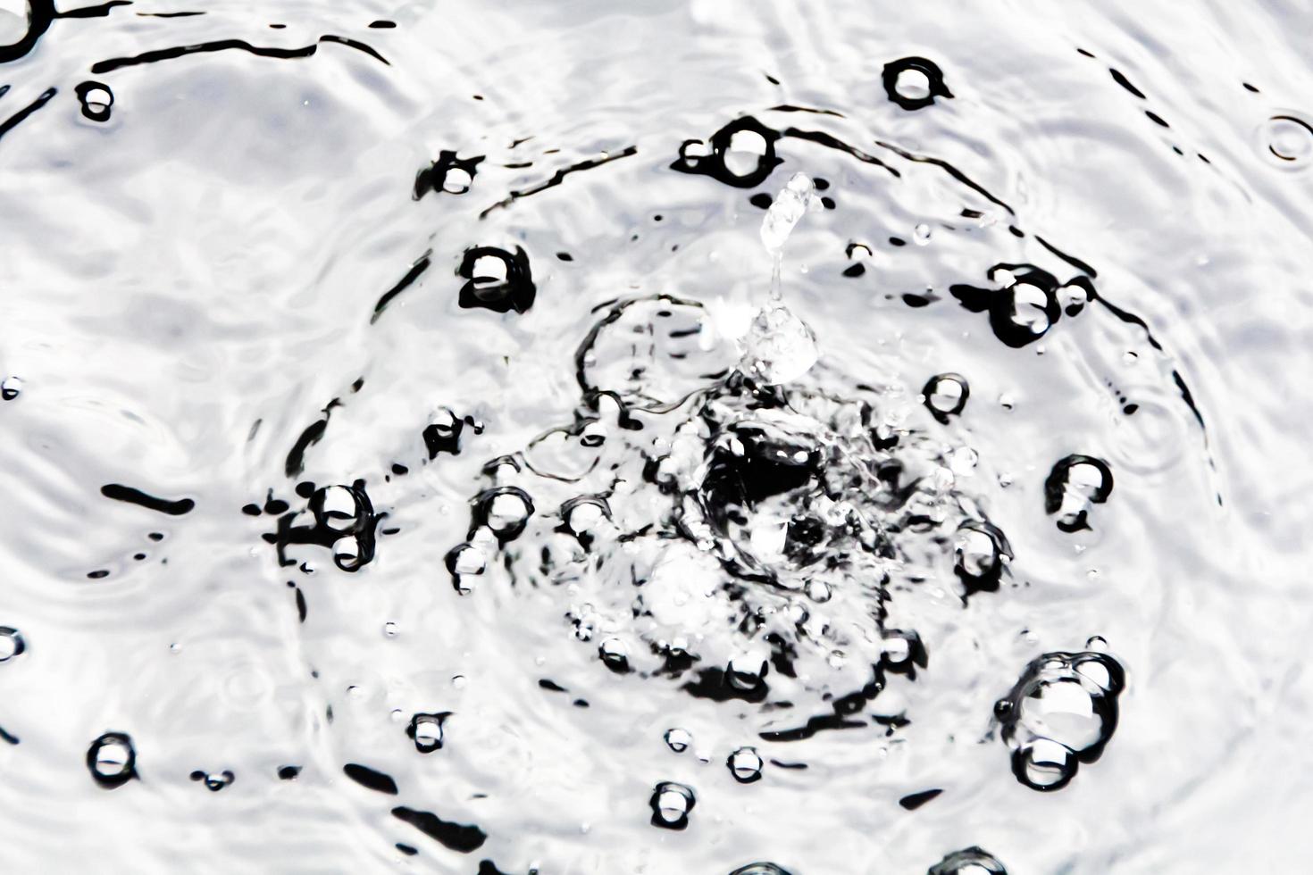 water druppels of water kralen vallen Aan de water oppervlakte veroorzaken de water oppervlakte naar verspreiden en schuim. foto