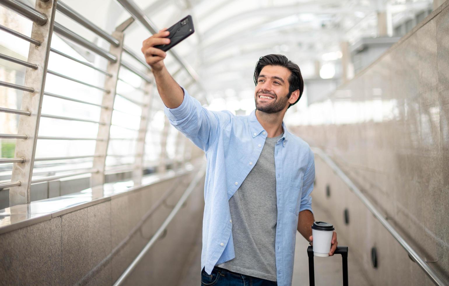 de Mens gebruik makend van smartphone selfies door zichzelf terwijl aan het wachten hun vriend Bij de luchthaven. foto