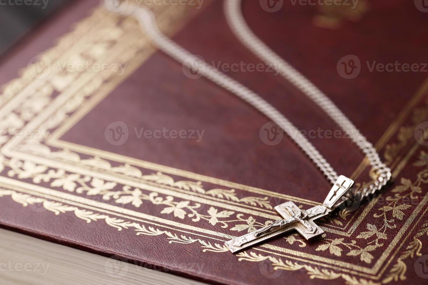 zilver ketting met kruisbeeld kruis Aan christen heilig Bijbel boek Aan zwart houten tafel. vragen zegeningen van god met de macht van heiligheid, welke brengt geluk foto