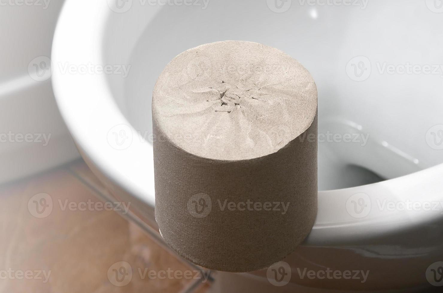 een rollen van grijs toilet papier leugens Aan een wit keramisch toilet in de badkamer foto