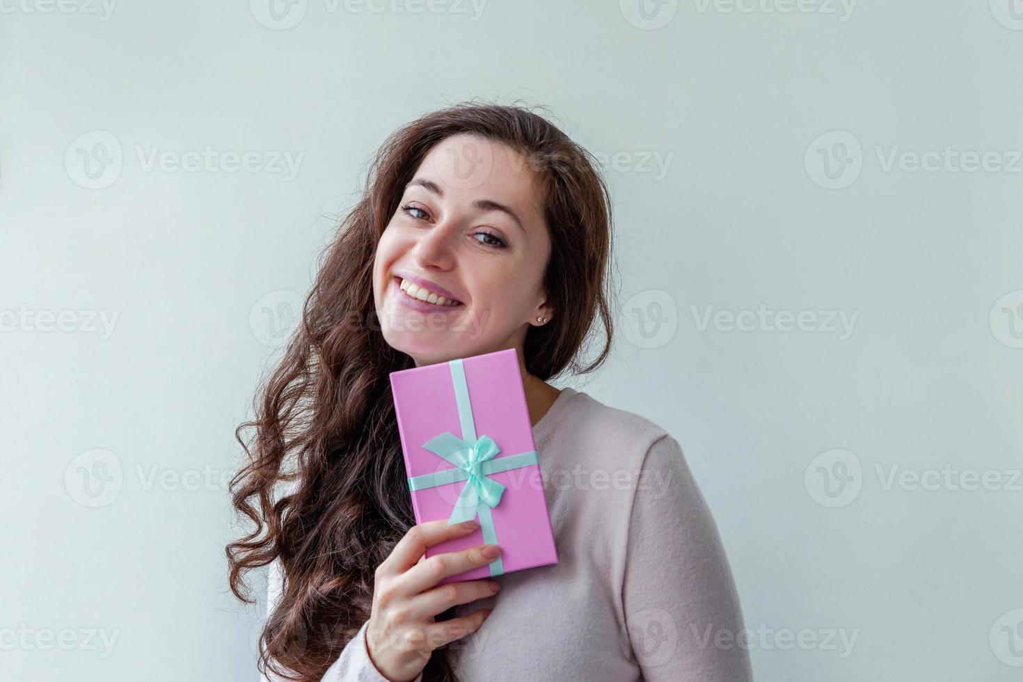 jong positief vrouw Holding klein roze geschenk doos geïsoleerd Aan wit achtergrond. voorbereiding voor vakantie. meisje op zoek gelukkig en opgewonden. Kerstmis verjaardag Valentijn viering Cadeau concept. foto
