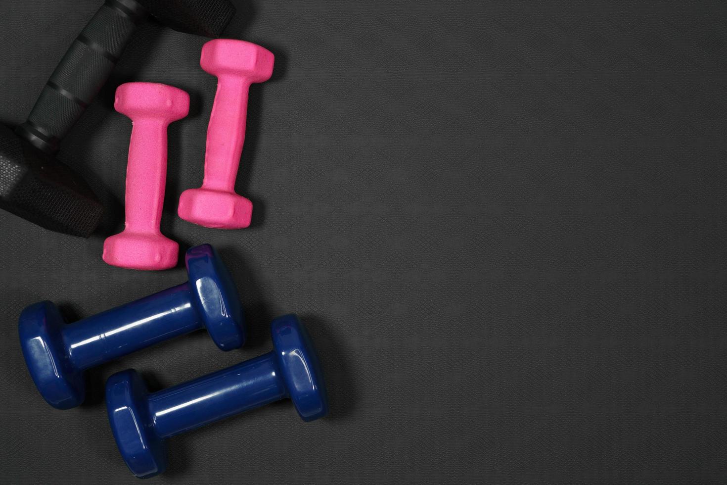 roze en zwart blauw halter achtergrond Aan zwart rubber achtergrond.fitness uitrusting achtergrond concept foto