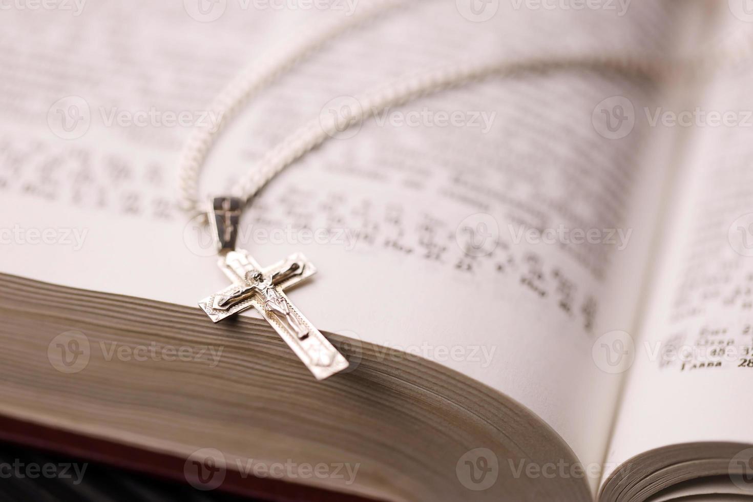 zilver ketting met kruisbeeld kruis Aan christen heilig Bijbel boek Aan zwart houten tafel. vragen zegeningen van god met de macht van heiligheid, welke brengt geluk foto