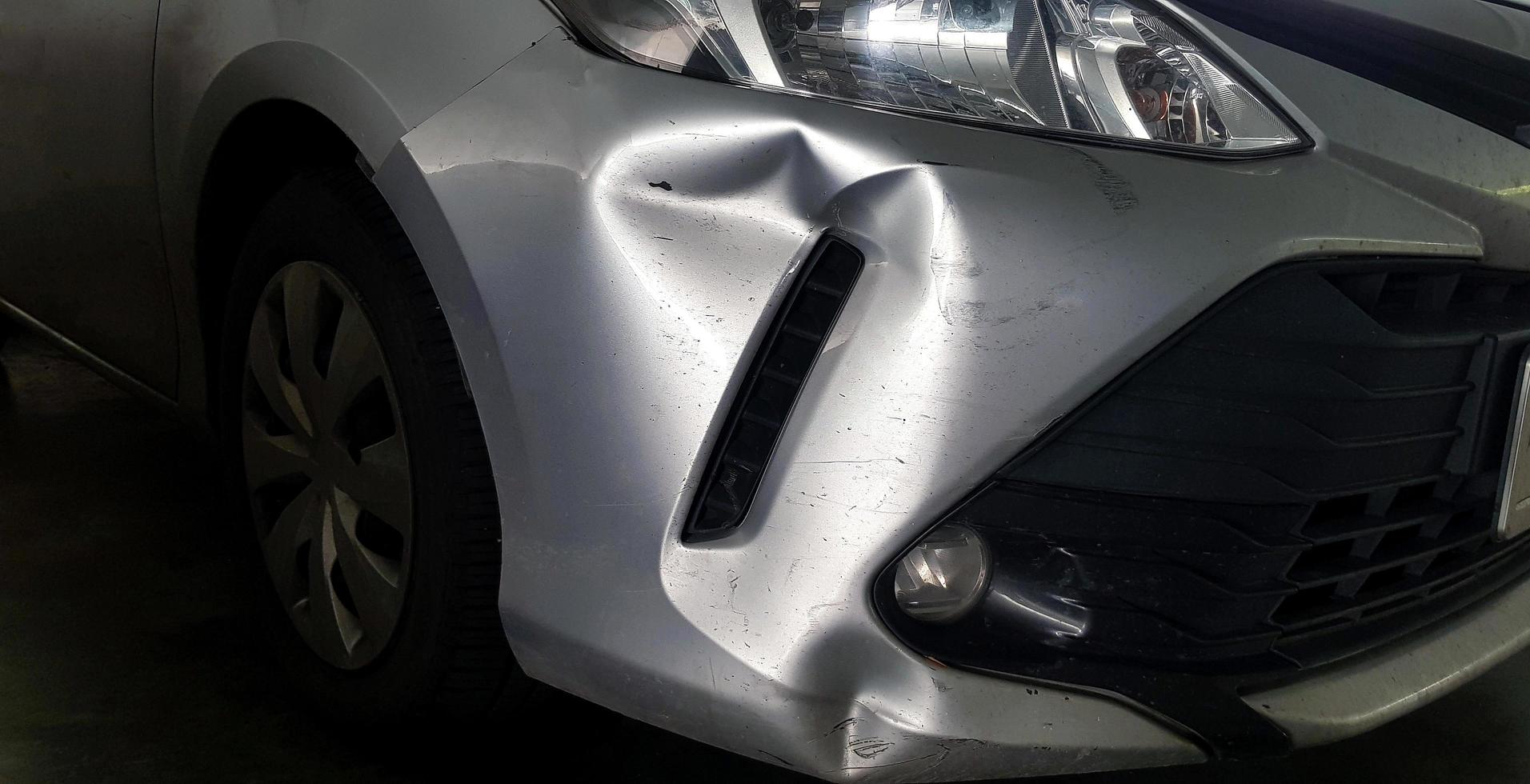 krassen of deuken Aan grijs, grijs of bronzen auto na ongeluk. beschadigd Aan gewond Aan voorkant bumper. foto