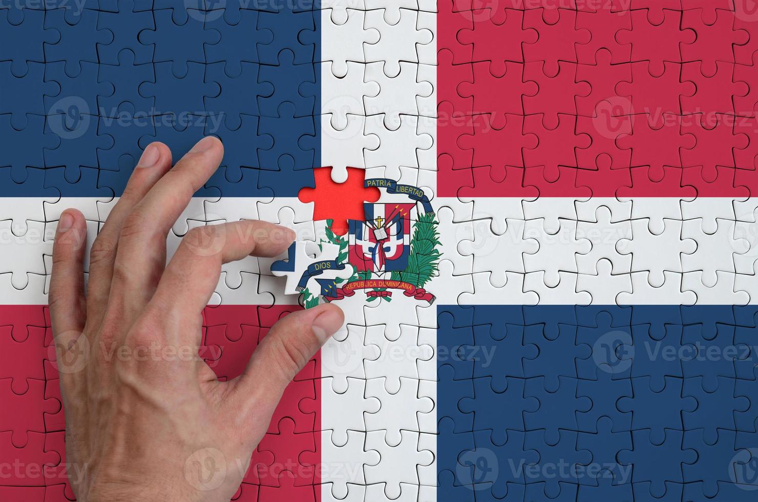 dominicaans republiek vlag is afgebeeld Aan een puzzel, welke de man's hand- voltooit naar vouwen foto