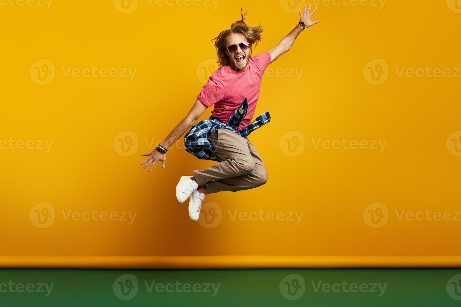 elegant jong Mens op zoek opgewonden terwijl jumping tegen geel achtergrond foto