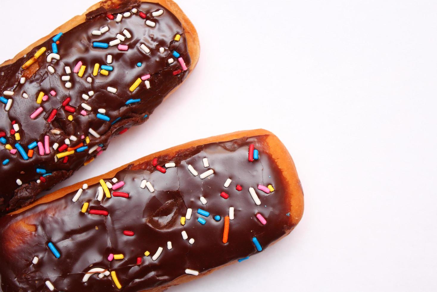 chocola donut bar bekroond met veelkleurig suiker vlokken. gelegd Aan een wit achtergrond foto
