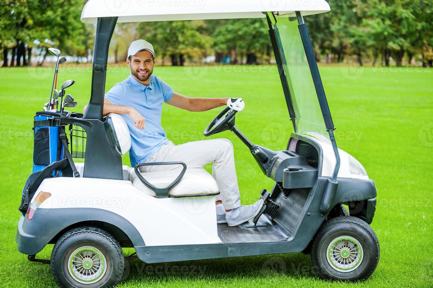 Mens het rijden golf kar. kant visie van knap jong Mens het rijden een golf kar en op zoek Bij camera foto