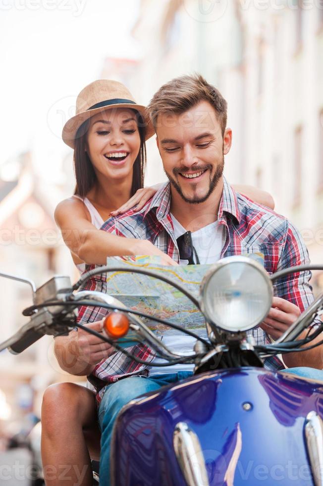 onderzoeken kaart samen. mooi jong paar zittend Aan scooter samen en onderzoeken kaart foto