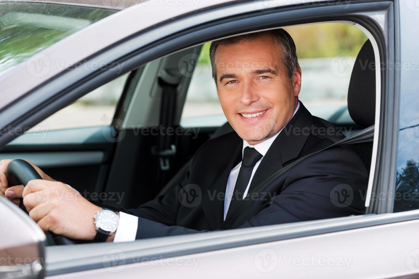 gevoel comfortabel in zijn nieuw auto. vrolijk volwassen Mens in formele kleding het rijden auto en glimlachen foto