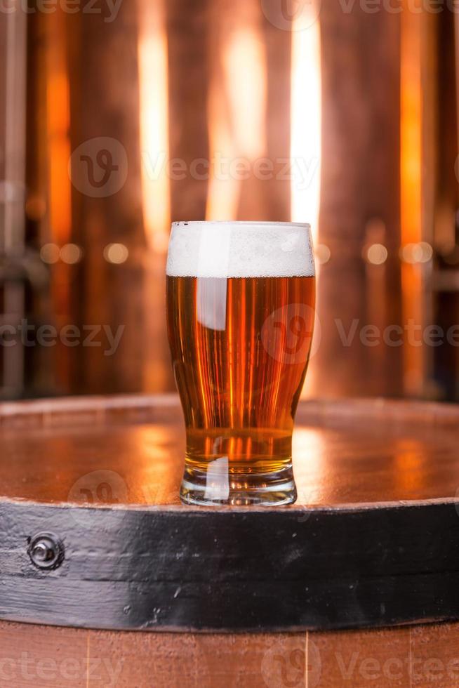 vers gebrouwen pils. detailopname van glas met bier staand Aan de houten vat met metaal houder in de achtergrond foto