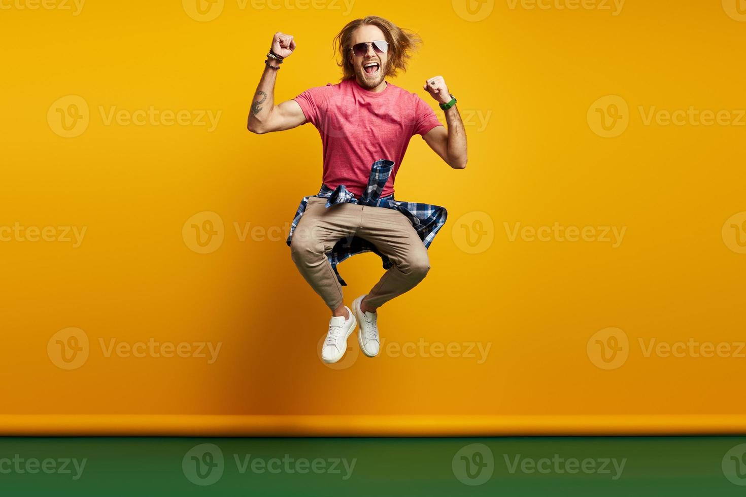 opgewonden jong Mens gebaren terwijl jumping tegen geel achtergrond foto