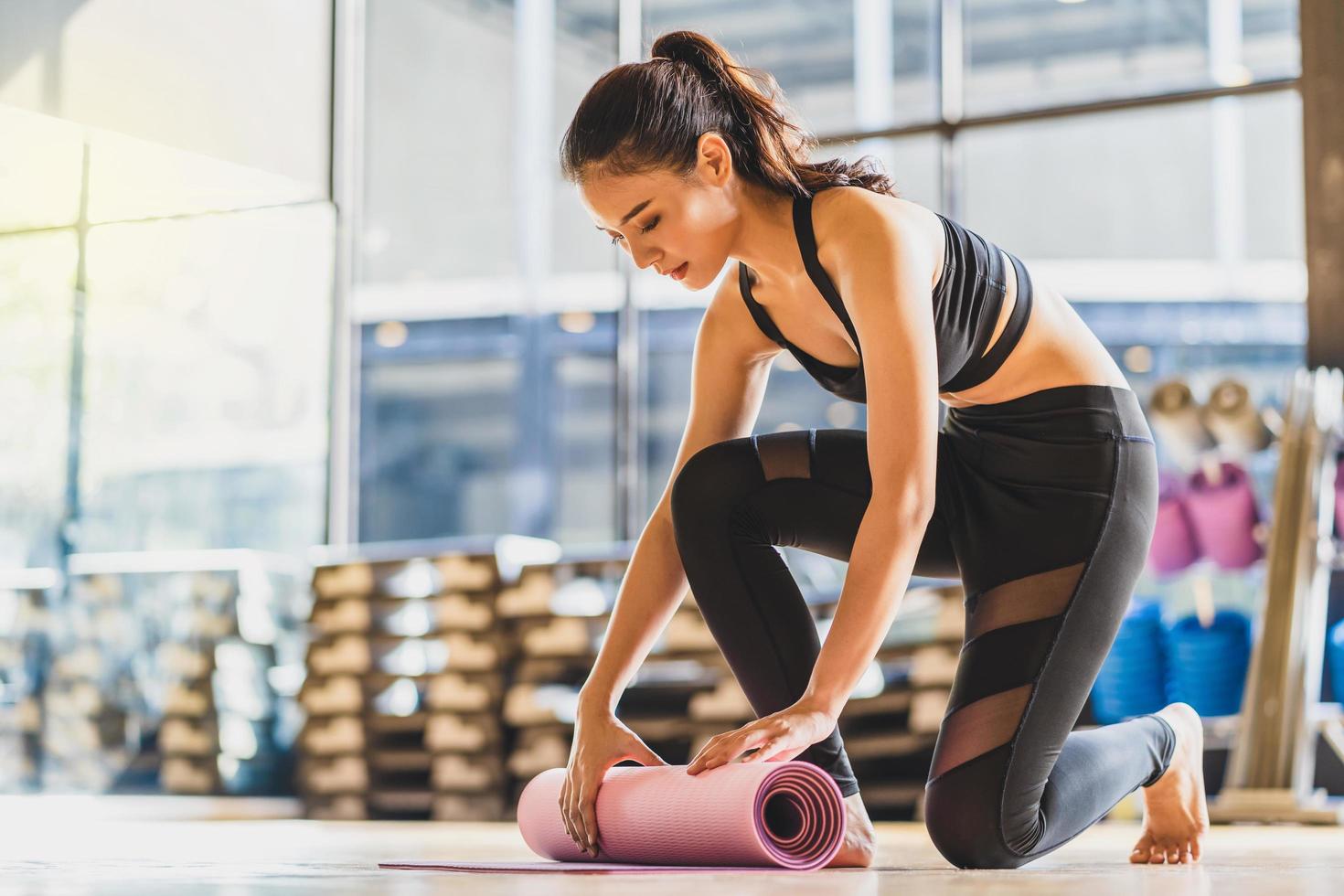 jonge Aziatische vrouw rollende yogamat na de training foto