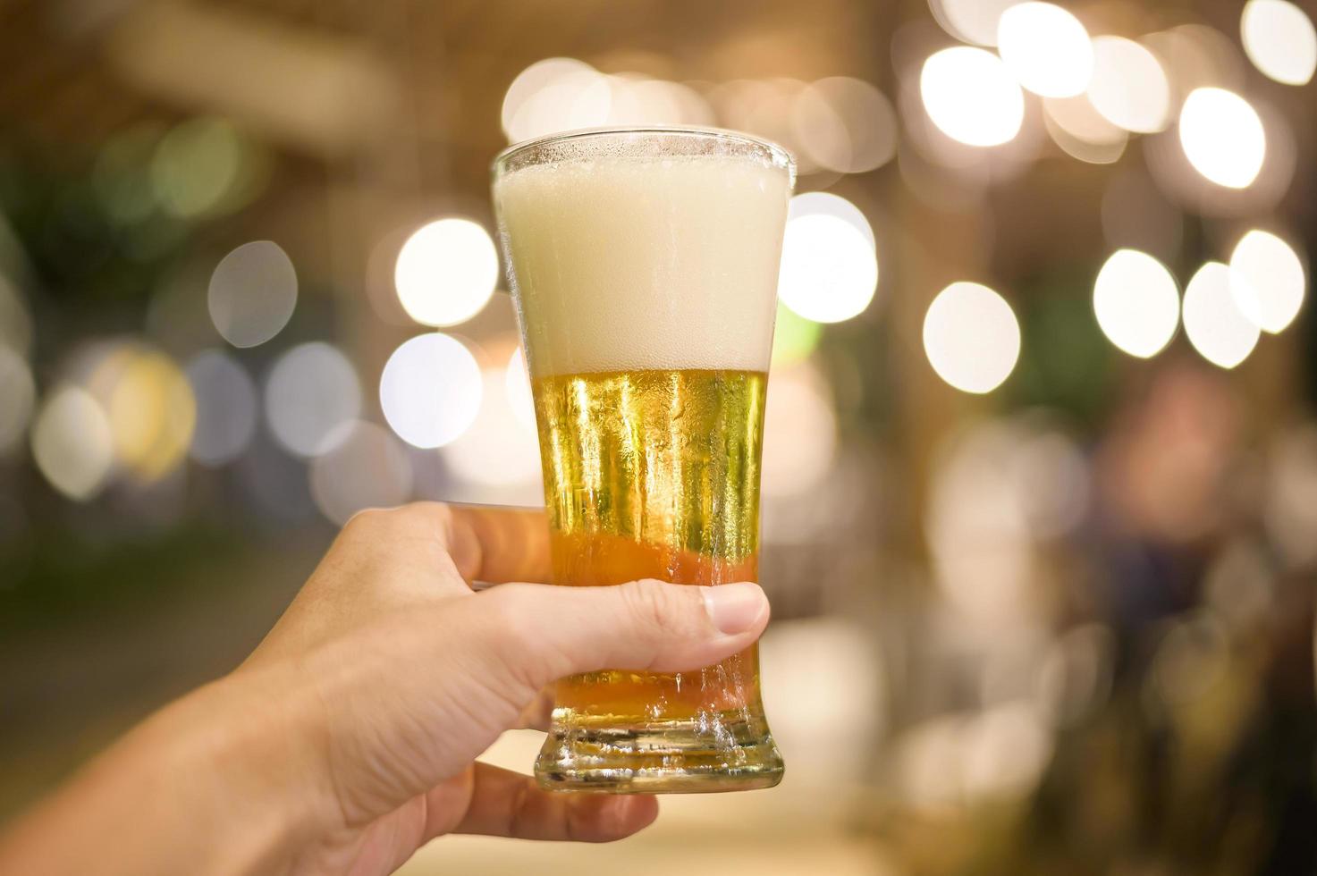 close-up van de hand met een glas bier om te vieren foto