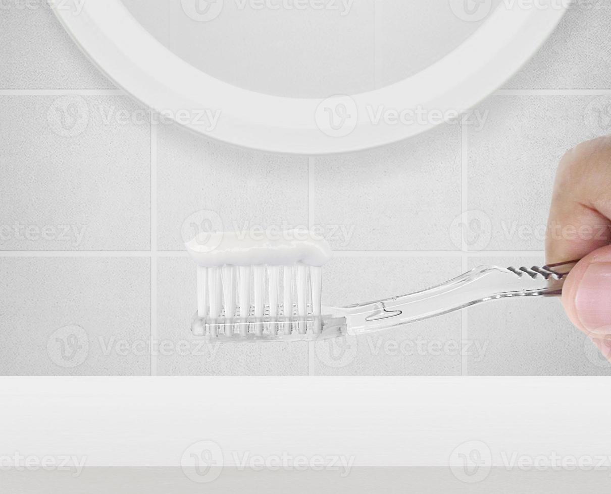 Mens schoonmaak tanden in de badkamer, hij is nemen zijn tandenborstel foto