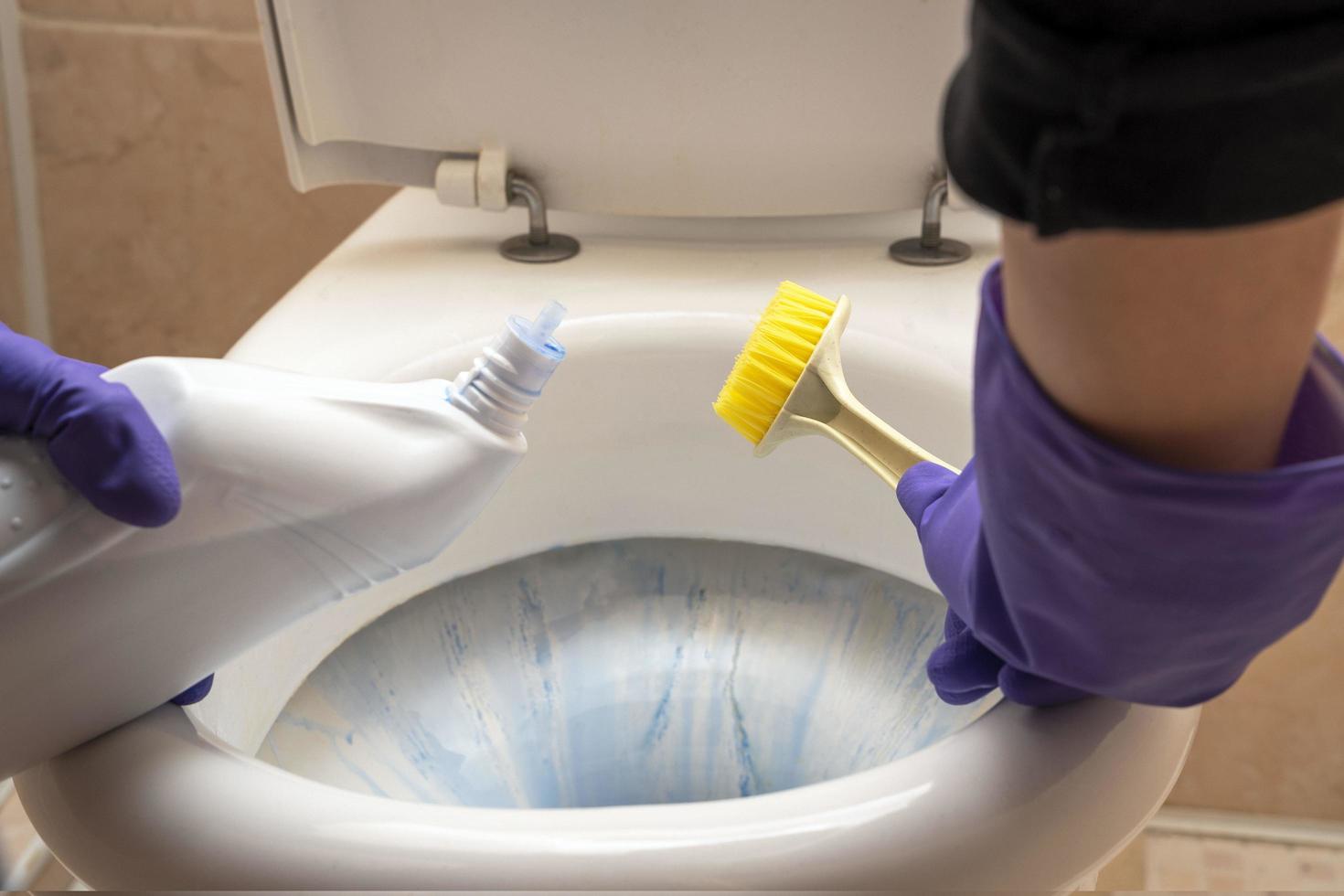 vrouwen handen wassen de toilet in de badkamer met wasmiddel, een borstel foto