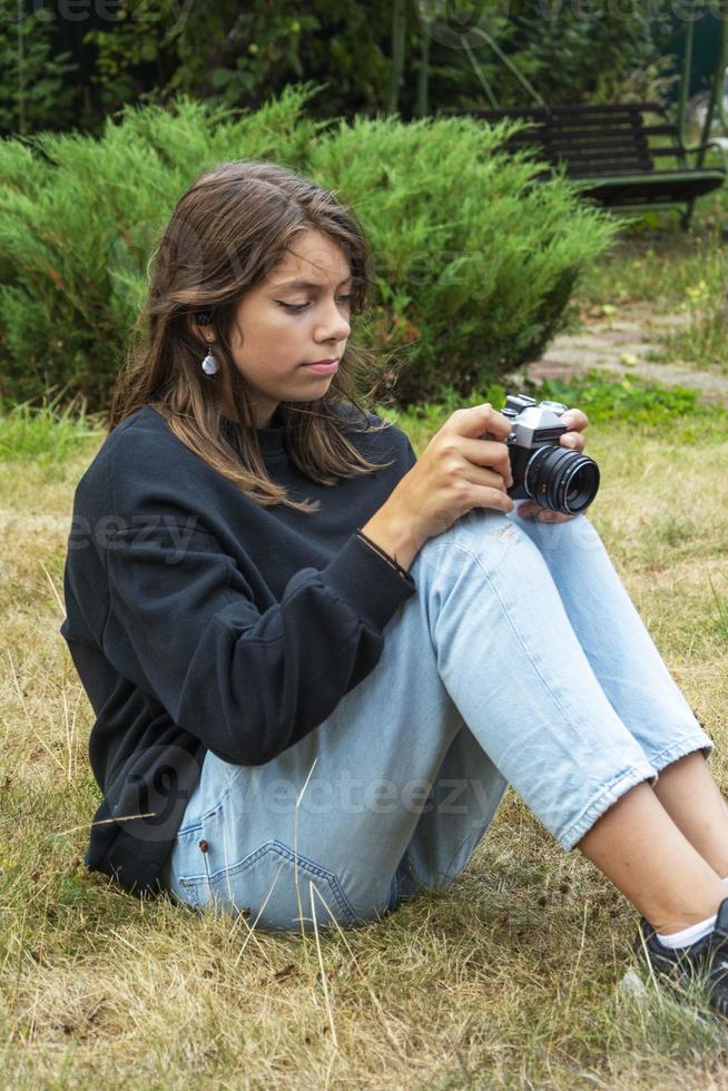 portret van een mooi tiener- meisje hebben pret met een camera. een meisje duurt afbeeldingen buitenshuis met een oud camera. foto