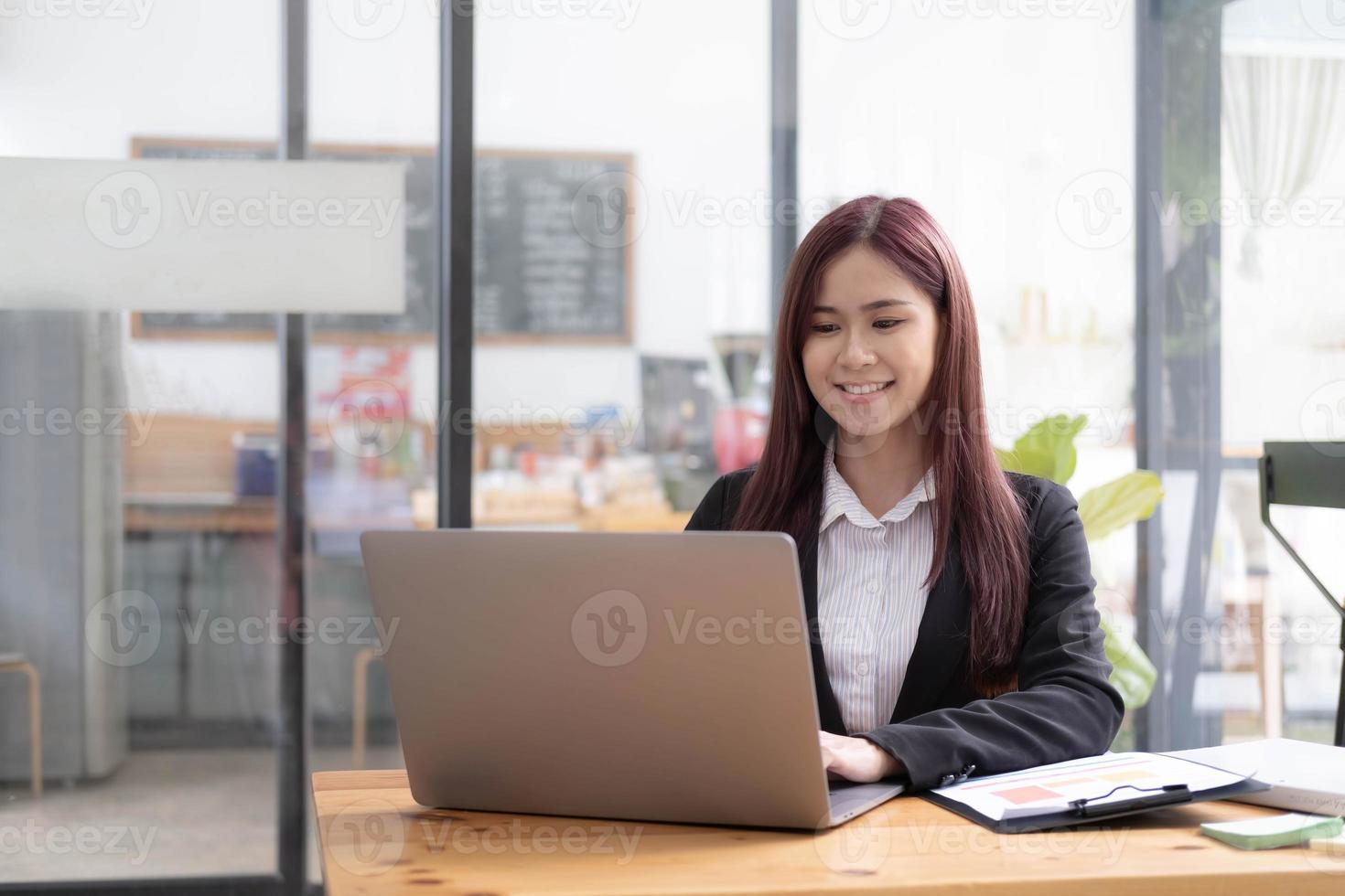 Aziatisch bedrijf vrouw gebruik makend van rekenmachine en laptop voor aan het doen wiskunde financiën Aan een kantoor bureau, belasting, rapport, boekhouding, statistieken, en analytisch Onderzoek concept foto