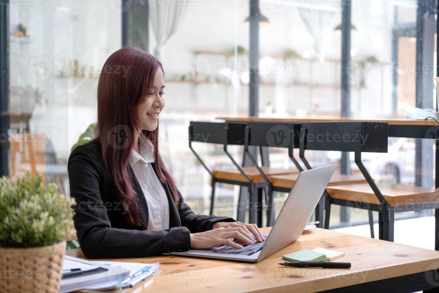 Aziatisch bedrijf vrouw gebruik makend van rekenmachine en laptop voor aan het doen wiskunde financiën Aan een kantoor bureau, belasting, rapport, boekhouding, statistieken, en analytisch Onderzoek concept foto