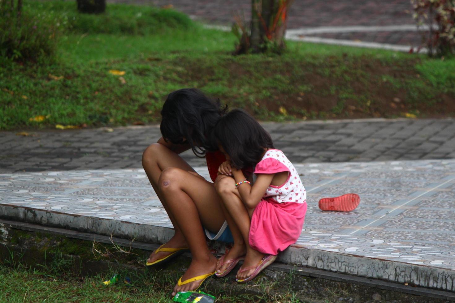 magelang, Indonesië, 2022 - foto van 2 weinig zussen en zussen wie zijn Aan de rand van de park in de middag