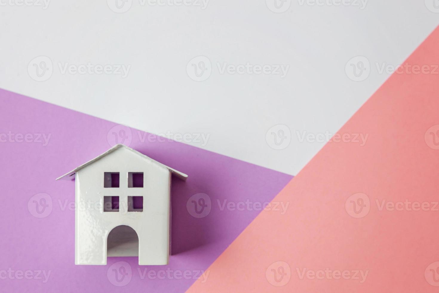 eenvoudig ontwerp met miniatuur wit speelgoed- huis geïsoleerd Aan wit paars roze pastel kleurrijk modieus meetkundig achtergrond. hypotheek eigendom verzekering droom huis concept. vlak leggen top visie kopiëren ruimte. foto