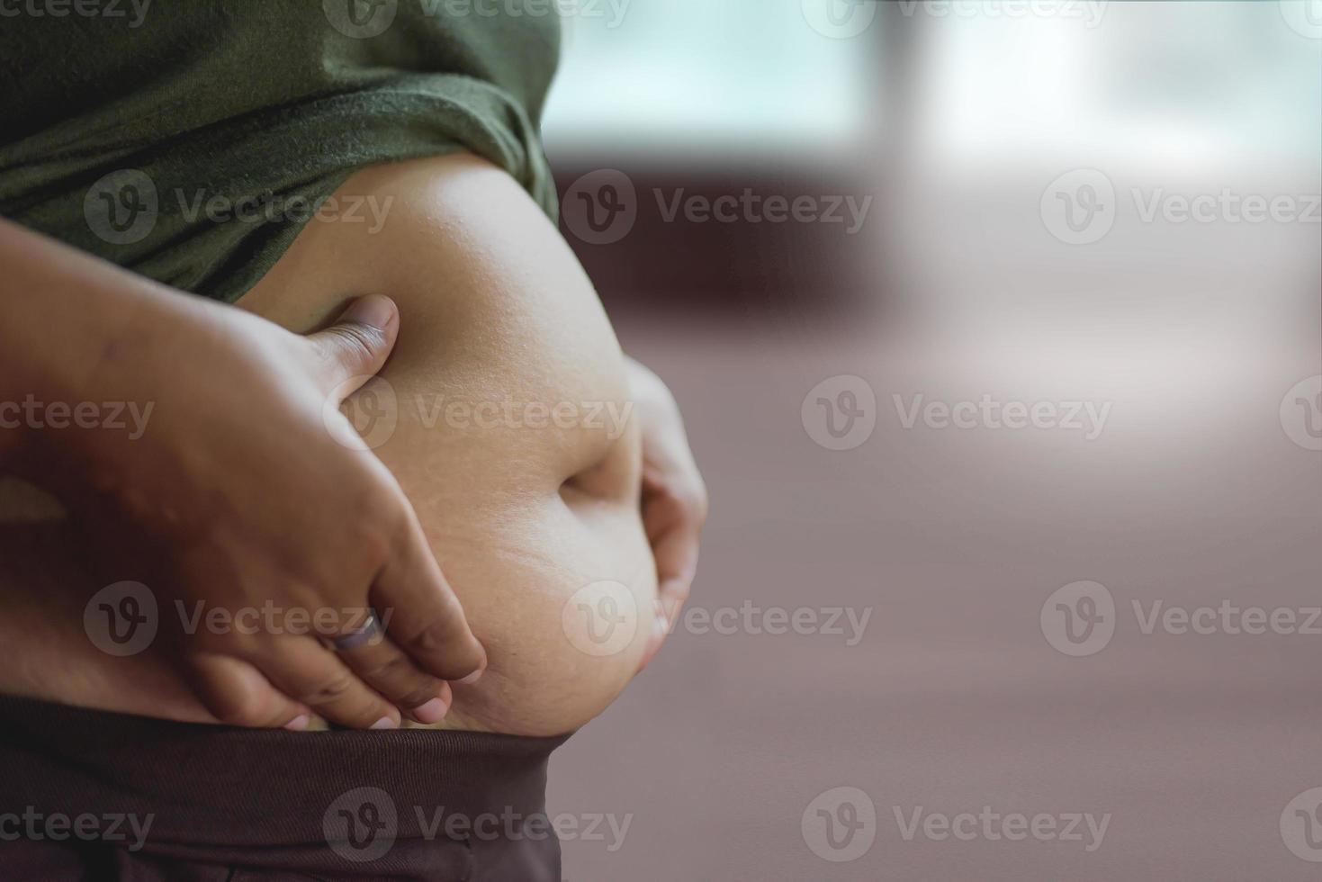 vrouw meten haar buik dik met haar handen. foto