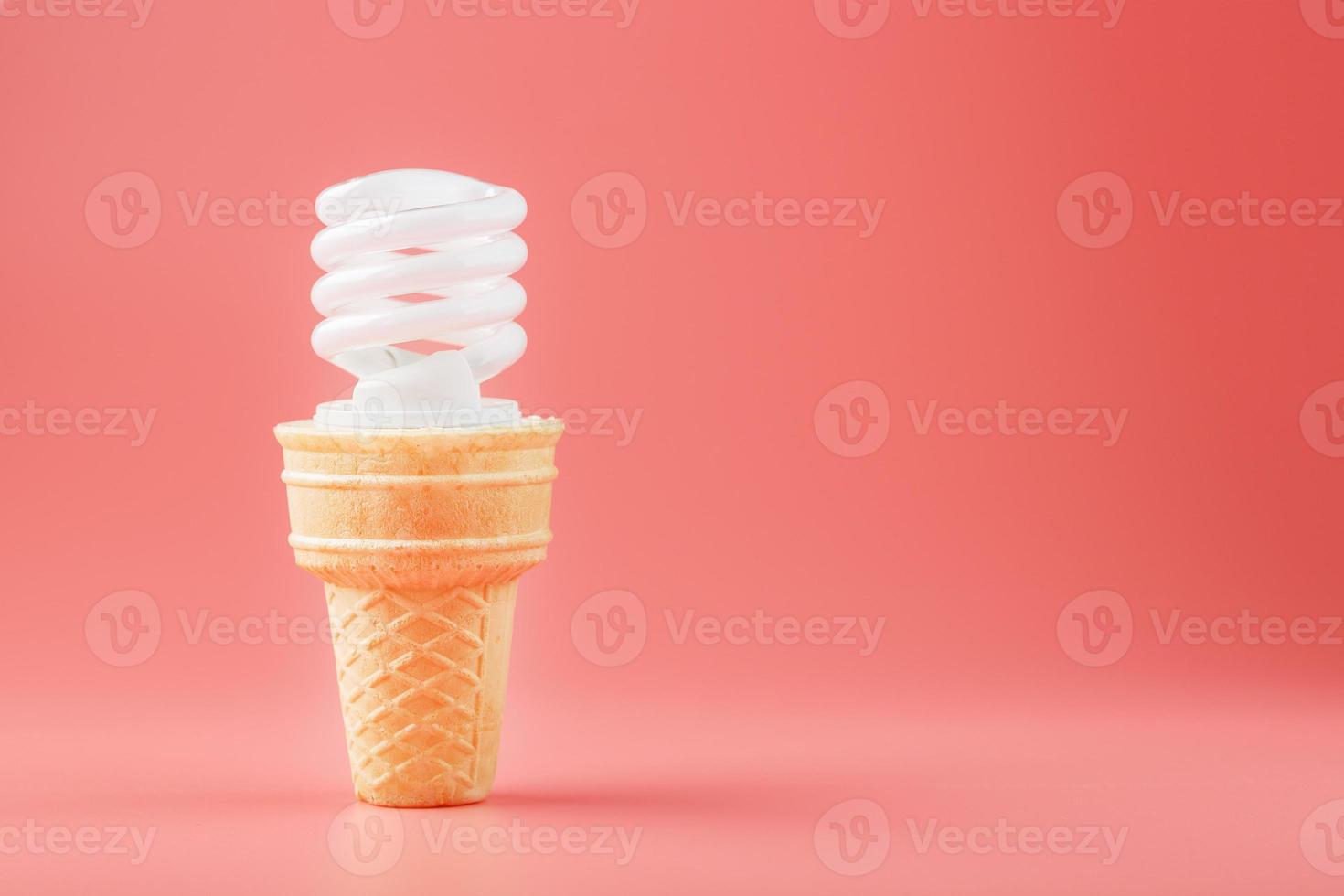 energiebesparend schroef licht ijs room in een wafel ijshoorntje Aan een roze achtergrond. foto